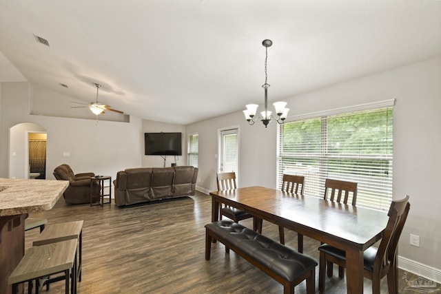 dining space featuring arched walkways, vaulted ceiling, ceiling fan with notable chandelier, dark wood-style floors, and visible vents