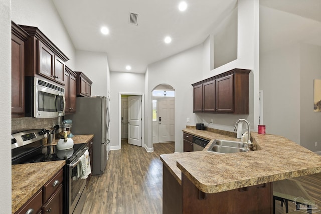 kitchen with tasteful backsplash, a sink, appliances with stainless steel finishes, visible vents, and arched walkways