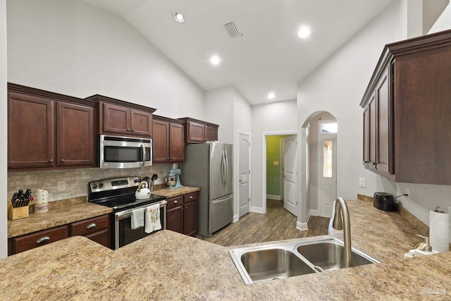 kitchen with decorative backsplash, a sink, visible vents, stainless steel appliances, and arched walkways