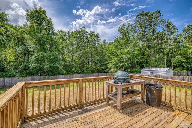 wooden terrace with an outdoor structure, a lawn, and a fenced backyard