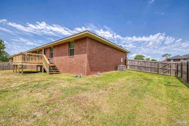 back of property with a wooden deck, stairway, a fenced backyard, a lawn, and brick siding