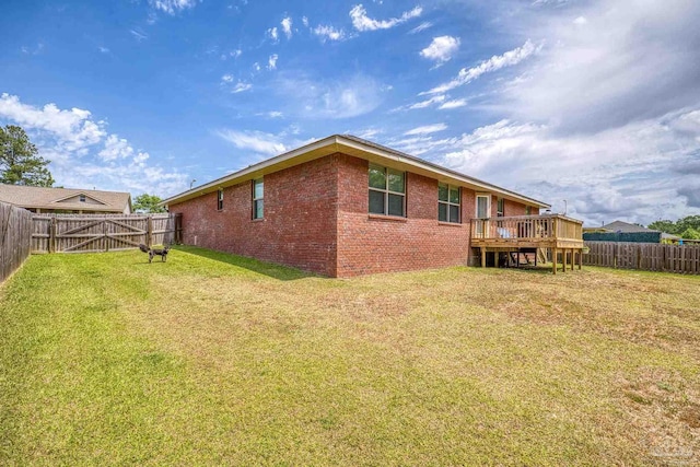exterior space featuring a deck, brick siding, a fenced backyard, and a yard
