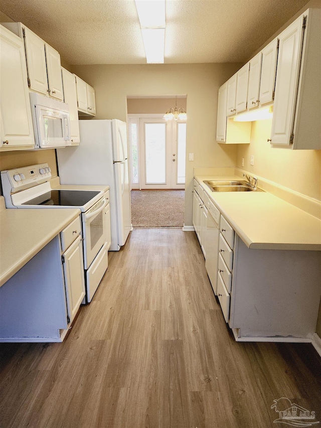 kitchen with white cabinetry, white appliances, decorative light fixtures, and sink