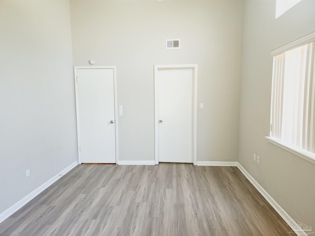 unfurnished bedroom with a towering ceiling and light hardwood / wood-style floors