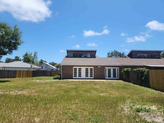 back of property featuring french doors and a lawn