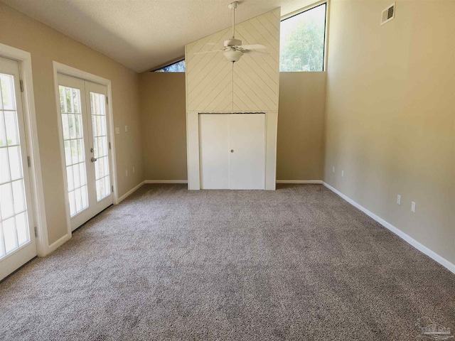 unfurnished living room featuring ceiling fan, carpet floors, a textured ceiling, vaulted ceiling, and french doors