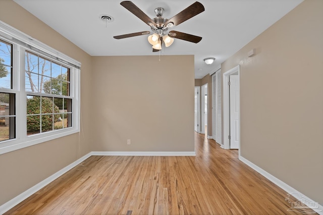 spare room with visible vents, a ceiling fan, light wood-type flooring, and baseboards