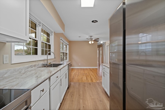 kitchen featuring a sink, light wood-style flooring, appliances with stainless steel finishes, and white cabinets