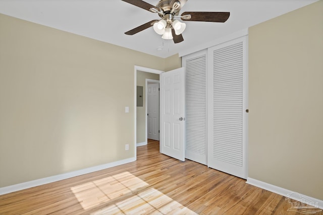 unfurnished bedroom with baseboards, electric panel, ceiling fan, a closet, and light wood-type flooring