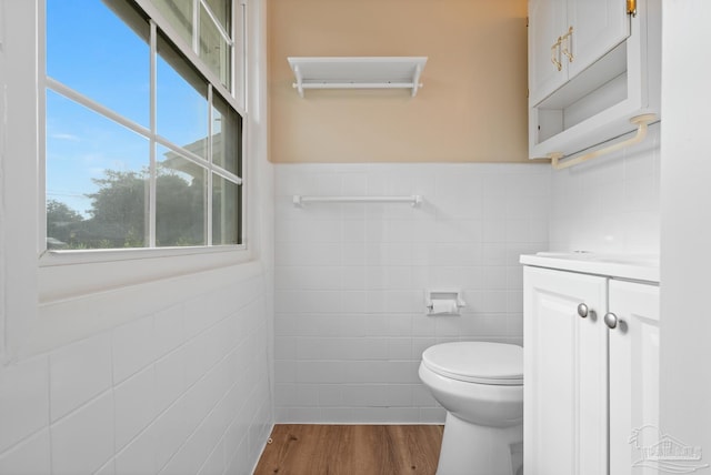 bathroom with vanity, wood finished floors, a wainscoted wall, tile walls, and toilet