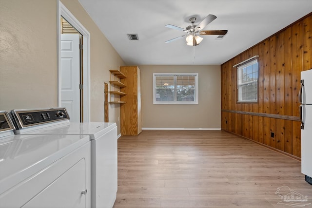 washroom with wooden walls, visible vents, light wood finished floors, ceiling fan, and washing machine and dryer