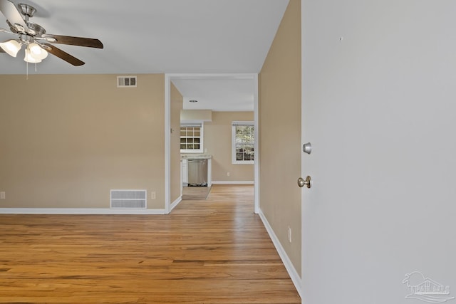 hallway with visible vents, light wood-style flooring, and baseboards