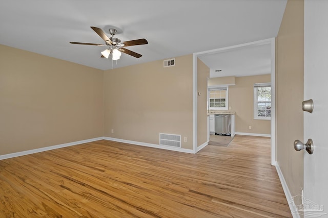 empty room with light wood-type flooring, visible vents, baseboards, and a ceiling fan