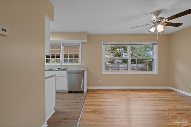 kitchen featuring ceiling fan, light wood-type flooring, stainless steel dishwasher, white cabinetry, and a sink