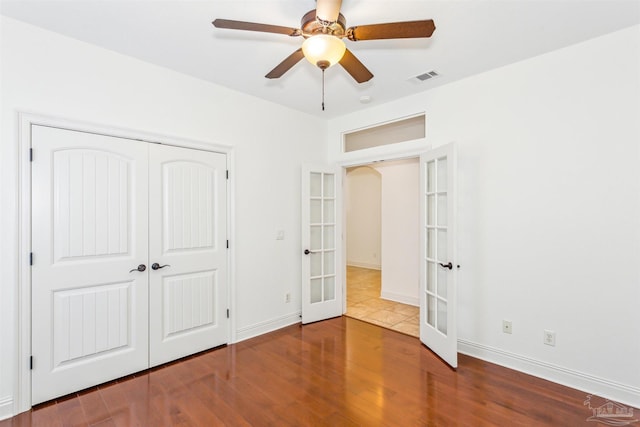 unfurnished bedroom featuring french doors, a closet, ceiling fan, and hardwood / wood-style floors