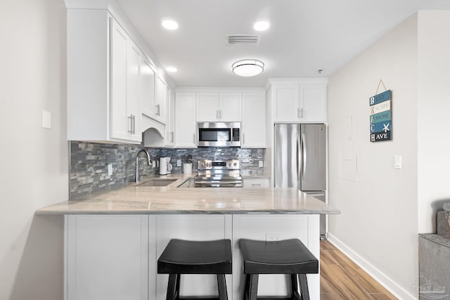 kitchen featuring sink, kitchen peninsula, white cabinets, and appliances with stainless steel finishes