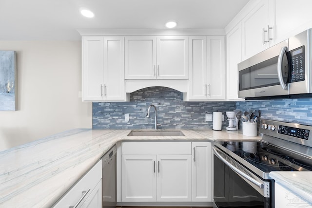 kitchen with sink, white cabinets, decorative backsplash, stainless steel appliances, and light stone countertops