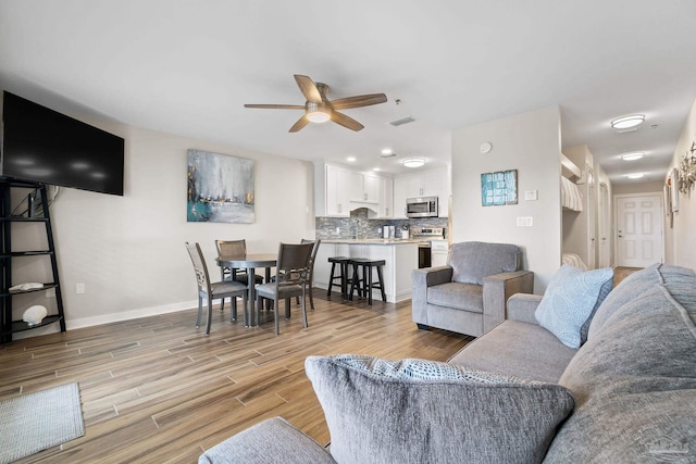 living room featuring ceiling fan and light hardwood / wood-style floors