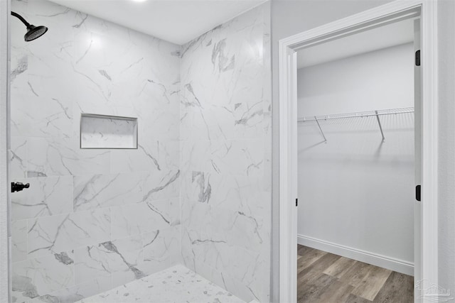 bathroom with a tile shower and wood-type flooring