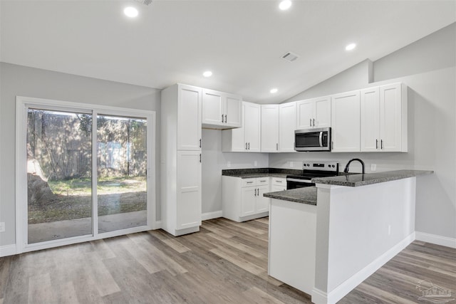 kitchen featuring appliances with stainless steel finishes, vaulted ceiling, light hardwood / wood-style flooring, and white cabinetry