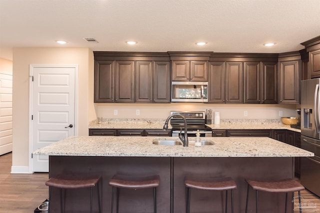 kitchen with a kitchen island with sink and stainless steel appliances