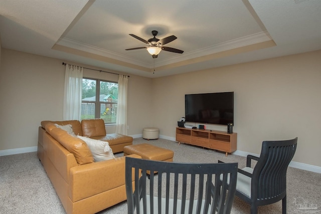 carpeted living room with ornamental molding, ceiling fan, and a raised ceiling