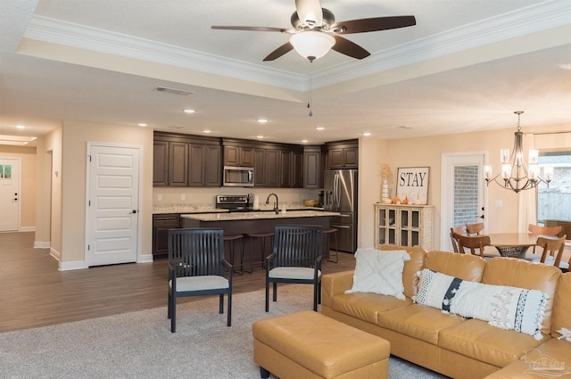 living room featuring ornamental molding, ceiling fan with notable chandelier, hardwood / wood-style flooring, and a tray ceiling