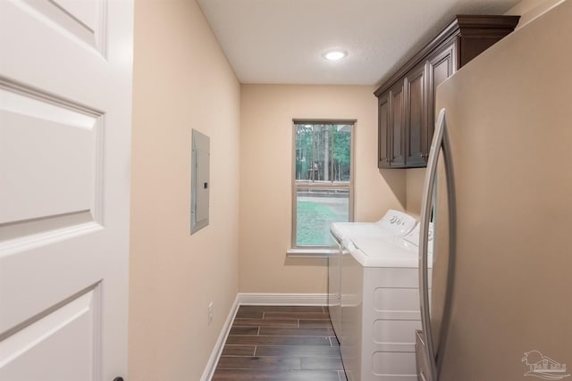 washroom with electric panel, a textured ceiling, dark hardwood / wood-style floors, cabinets, and washing machine and clothes dryer