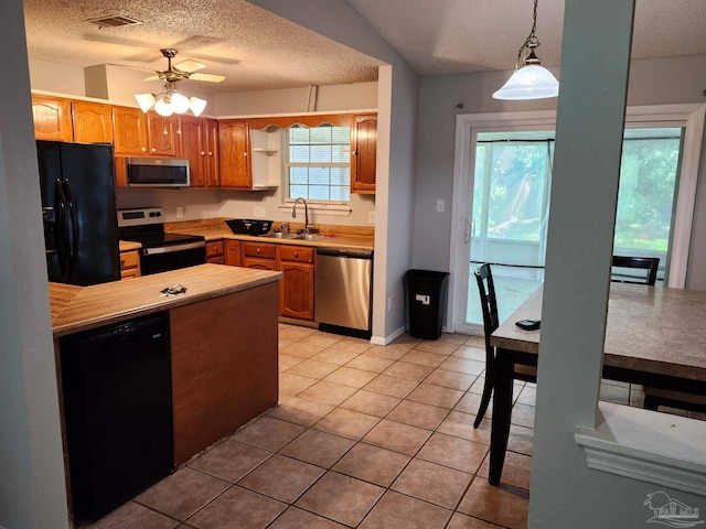 kitchen with pendant lighting, a textured ceiling, light tile patterned floors, and black appliances