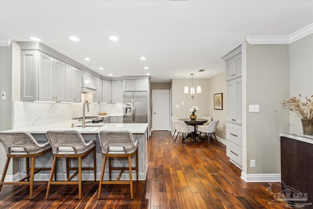 kitchen featuring stainless steel refrigerator with ice dispenser, a kitchen breakfast bar, kitchen peninsula, pendant lighting, and dark hardwood / wood-style flooring