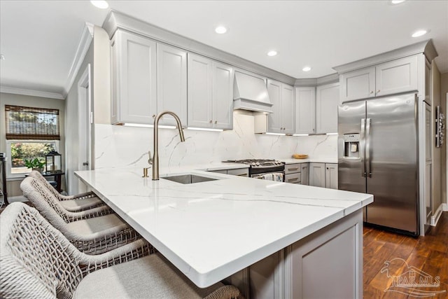 kitchen featuring appliances with stainless steel finishes, sink, a kitchen breakfast bar, kitchen peninsula, and custom range hood