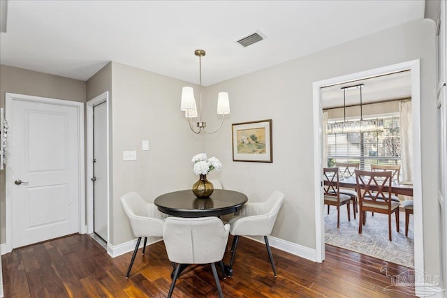 dining space featuring dark wood-type flooring and a notable chandelier