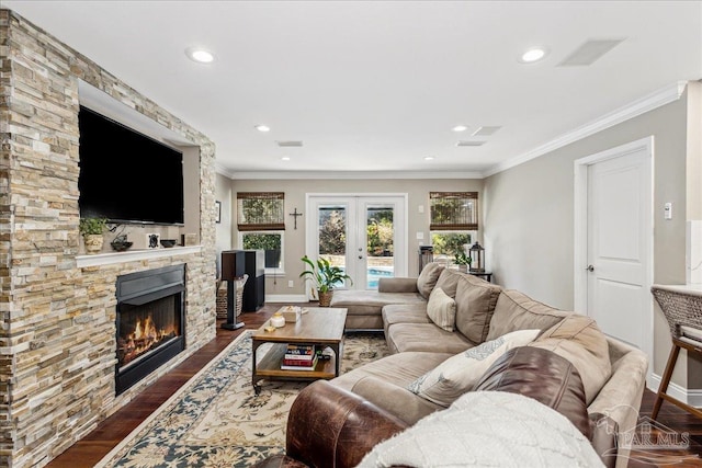 living room with a stone fireplace, crown molding, and dark hardwood / wood-style flooring