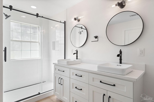 bathroom with a sink, visible vents, double vanity, and a shower stall