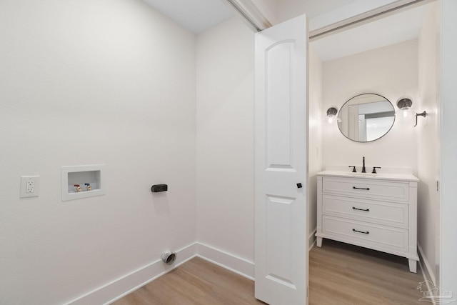 clothes washing area featuring laundry area, light wood-style flooring, a sink, and washer hookup