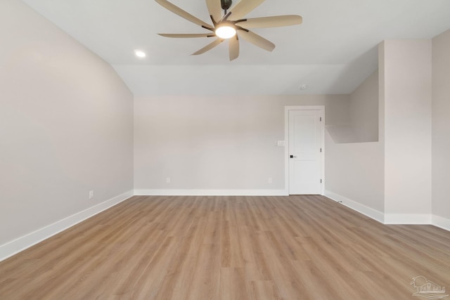 spare room featuring vaulted ceiling, baseboards, light wood finished floors, and ceiling fan