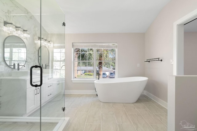 full bath featuring vanity, a soaking tub, baseboards, and a wealth of natural light