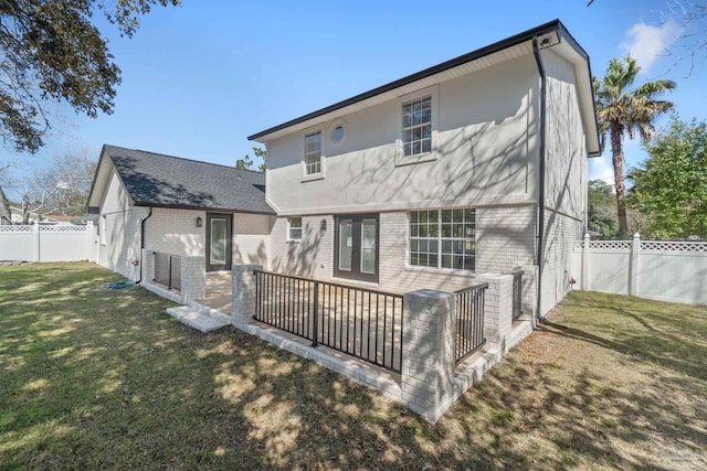 rear view of house with a lawn, a fenced backyard, brick siding, and a patio area