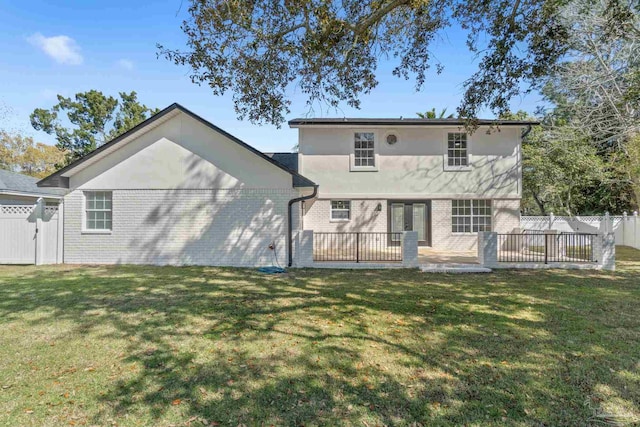 back of house featuring a yard, a patio, brick siding, and fence