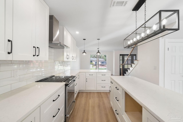 kitchen with visible vents, tasteful backsplash, stainless steel range with electric cooktop, wall chimney exhaust hood, and light wood finished floors