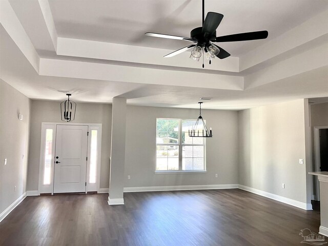 entryway featuring a tray ceiling, dark wood-type flooring, and ceiling fan with notable chandelier