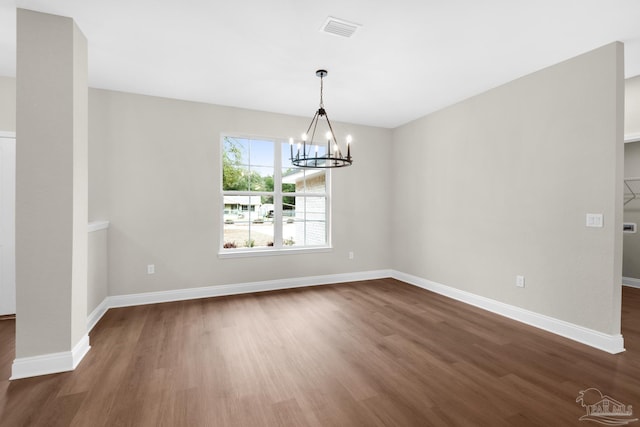 unfurnished dining area featuring dark wood-type flooring and a notable chandelier