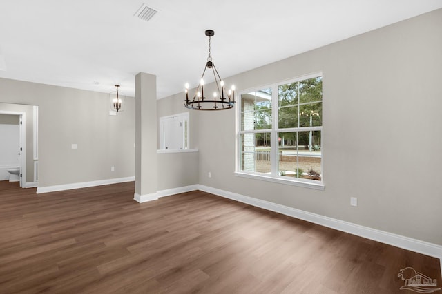 unfurnished dining area with dark hardwood / wood-style floors and an inviting chandelier