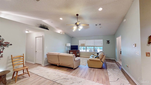 living room featuring a textured ceiling, ceiling fan, light hardwood / wood-style flooring, and vaulted ceiling