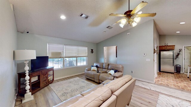 living room featuring ceiling fan, lofted ceiling, a textured ceiling, and light hardwood / wood-style flooring