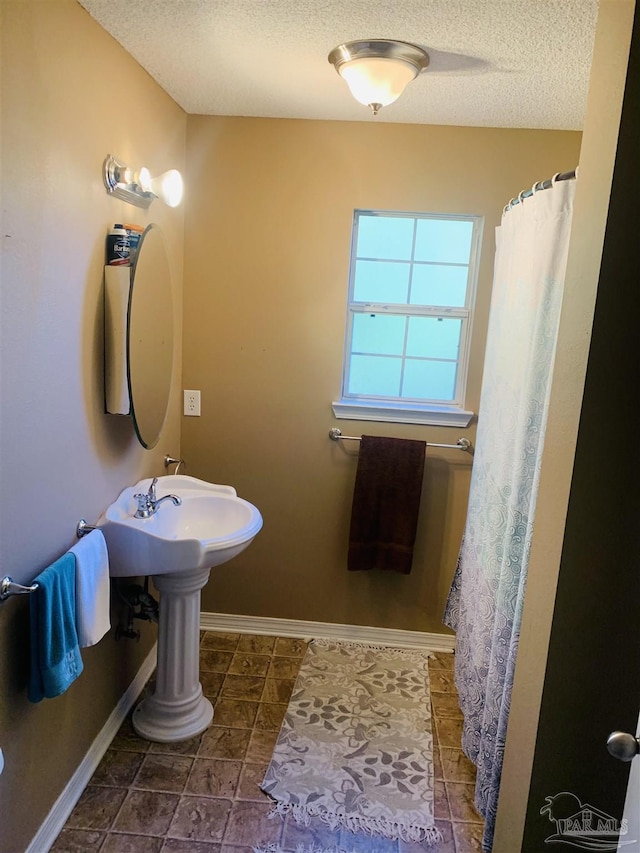 bathroom with a textured ceiling and baseboards