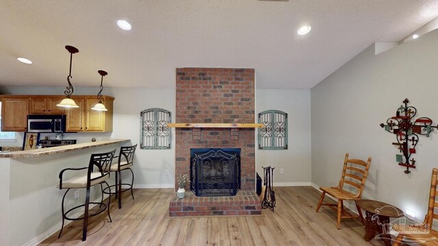 living area featuring a fireplace, light wood-style flooring, and baseboards