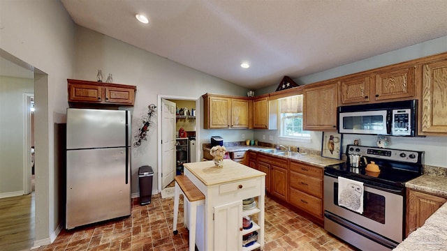 kitchen featuring appliances with stainless steel finishes, recessed lighting, brick floor, and a sink