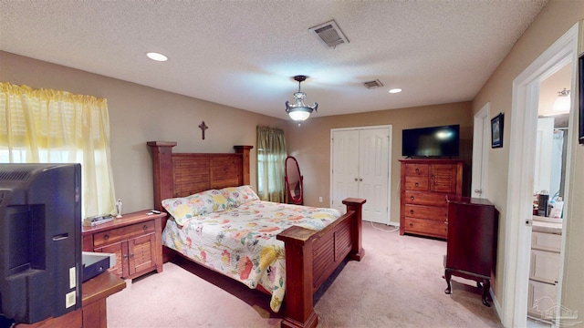 bedroom with a textured ceiling, light carpet, and a closet