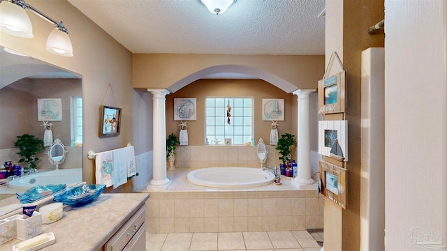 bathroom featuring tile patterned flooring, vanity, tiled bath, and decorative columns